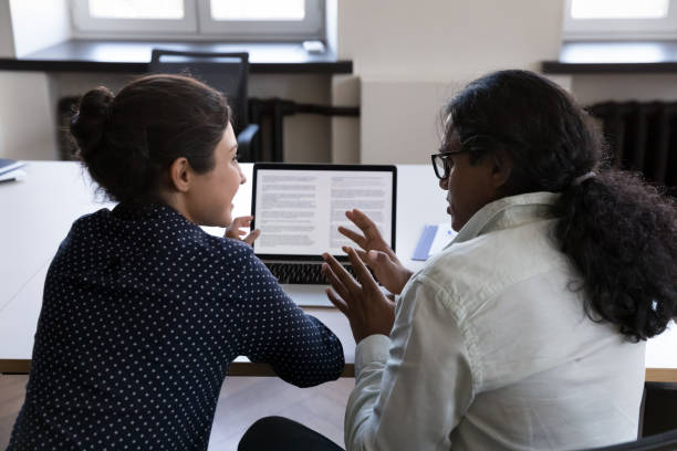 dois funcionários de escritório indianos compartilhando laptop na mesa de trabalho - teamwork concepts article communication - fotografias e filmes do acervo