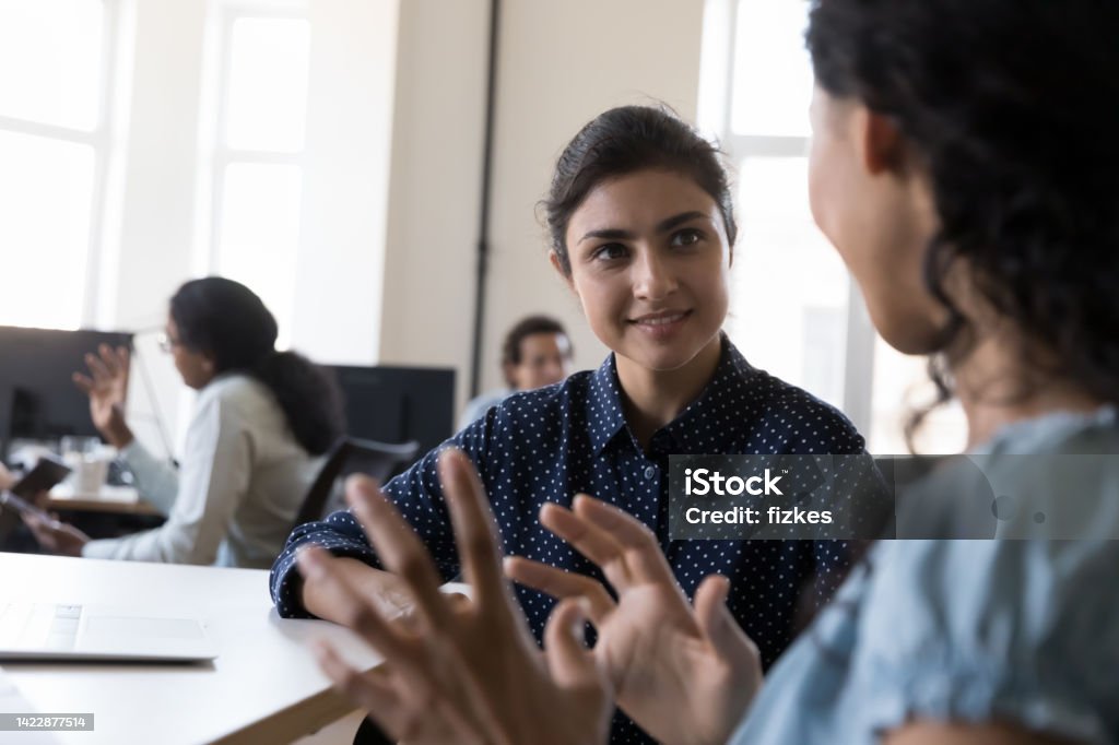 Happy Indian intern listening to mentor, consulting corporate teacher Happy Indian intern listening to mentor, consulting corporate teacher at shared office workplace in training center, discussing new professional skills, smiling. Business education, internship Mentorship Stock Photo