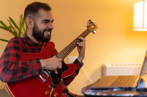 Young man Teaching/Learning online guitar classes at home