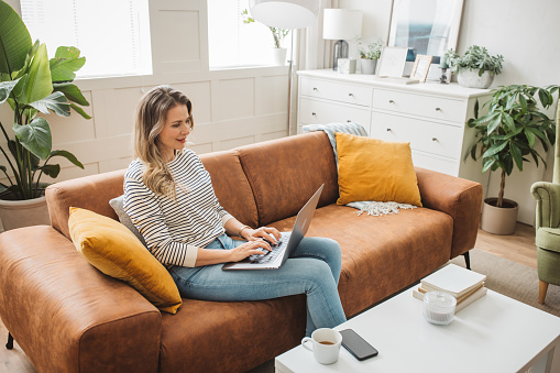 Mature woman using laptop while sitting on the sofa at home.