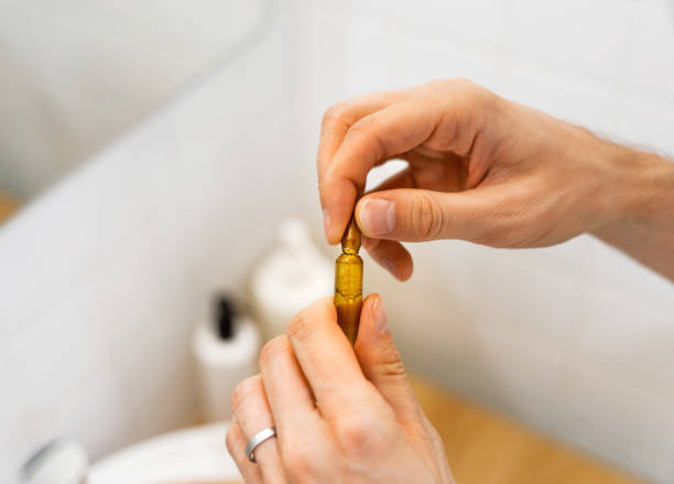 Male hands holding cosmetic ampoules with serum for hair growth, restoration beauty hair in a modern bright bathroom. Concept Hair loss, the problem of male baldness. Life style. manos masculinas sosteniendo ampollas cosméticas con suero para el crecimiento del cabello, restauración de belleza del cabello en un baño moderno y luminoso. concepto pérdida de cabello, el problema de la calvicie masculina. estilo de vida