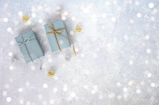 two grey giftboxes decorated silver and golden ribbons on the grey background, holiday concept, christmas, birthday, top view, copy space