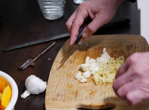 istock Man cuts garlic and ginger on wooden board 1422893291