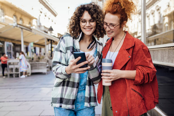 istock Two happy girls enjoying coffee while walking down the street 1422911465
