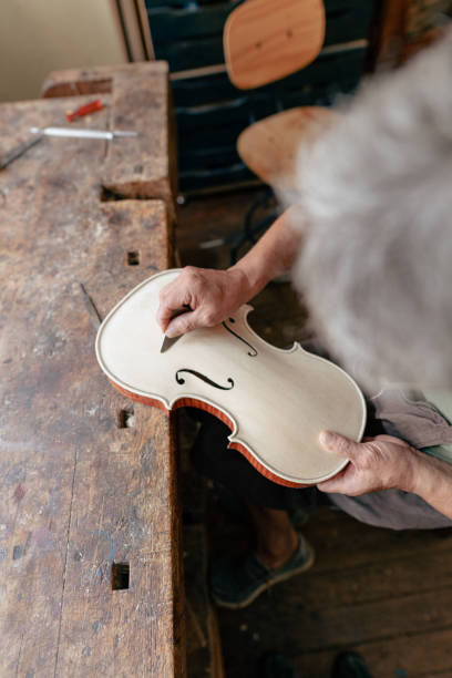 luthier tallando y esculpiendo los agujeros f un violín con un cuchillo - making craftsperson italian music musical instrument fotografías e imágenes de stock
