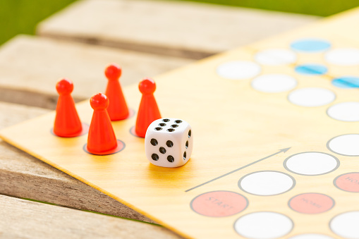 Details of a ludo board game being played outdoors
