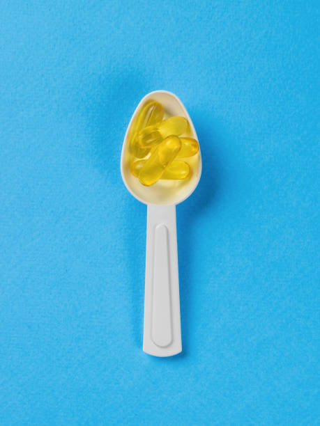 istock White plastic spoon with fish oil capsules on a blue background. Biologically active additive. 1422938160