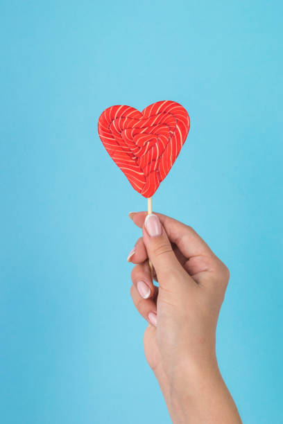istock A girl's hand with a beautiful heart-shaped candy on a blue background. 1422938164