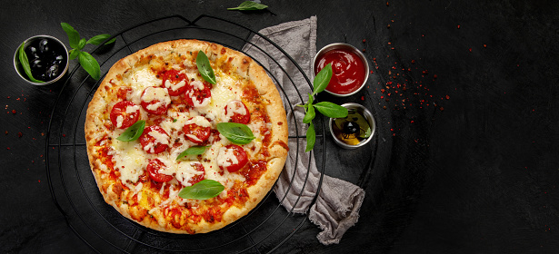 Freshly baked pizza on dark background. Tasty homemade food concept. Top view, copy space, panoramma