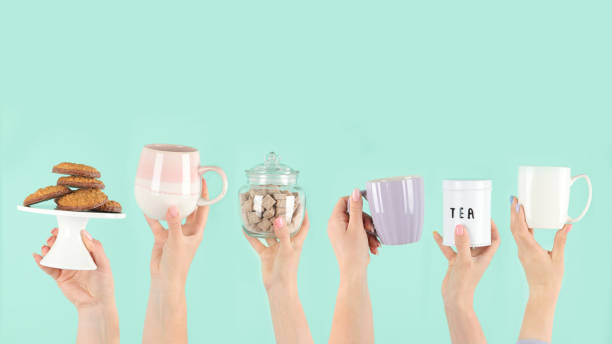 istock Arms raised up holding tea cup on green background. 1422948259