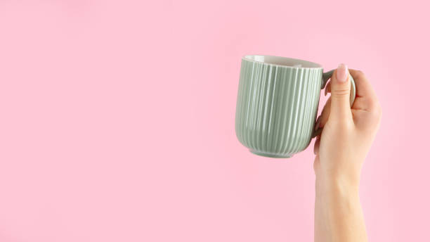 istock Arms raised up holding coffee cup on pink background. 1422948399