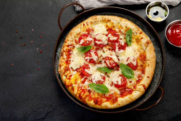 istock Freshly baked pizza on dark background. 1422948498