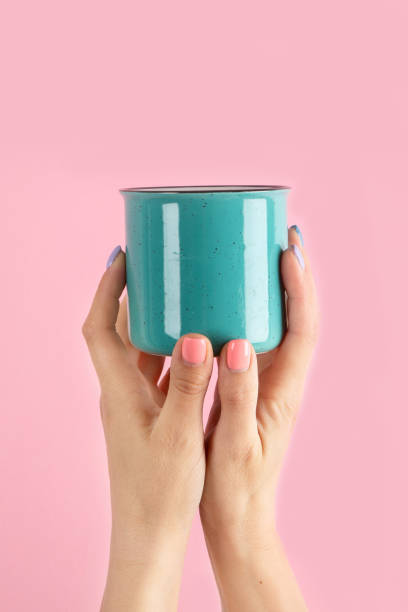 istock Arms raised up holding coffee cup on pink background. 1422948591