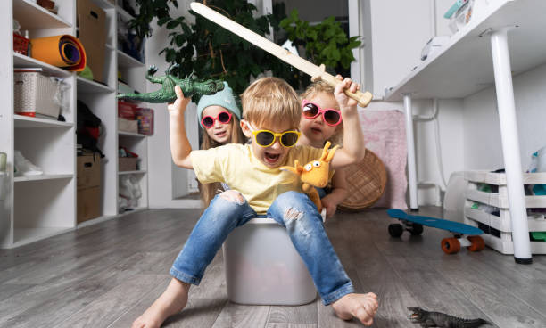 Children have fun and ride in a white plastic box. The room is a mess.