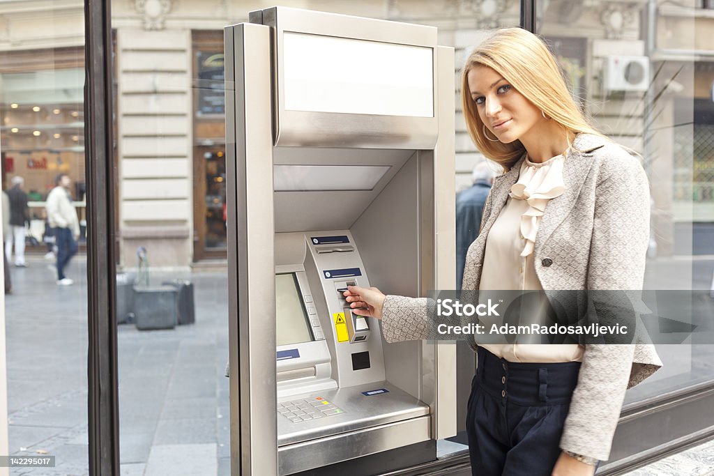 Woman using Bank ATM machine Young Woman using Bank ATM cashe machine on the street ATM Stock Photo