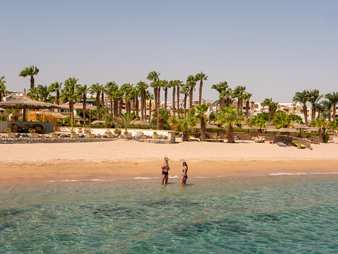 Hurghada, Egypt - September 22, 2021: People stand on the shores of the sandy beach of the Red Sea wearing masks for snorkeling.
