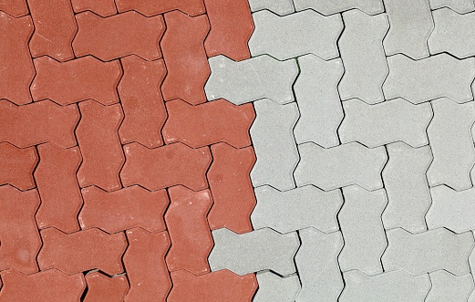 Red and gray interlocking concrete paver blocks. Irregular shaped tiles for outdoor pavement. Samples.