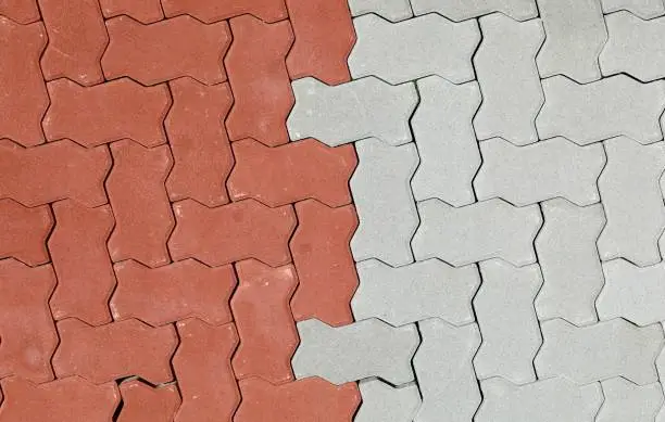 Photo of Red and gray interlocking concrete paver blocks. Irregular shaped tiles for outdoor pavement. Samples.