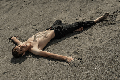 Young Man lying on sand in desert
