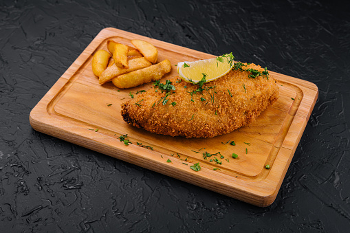 Breaded schnitzel with french fries on a cutting board