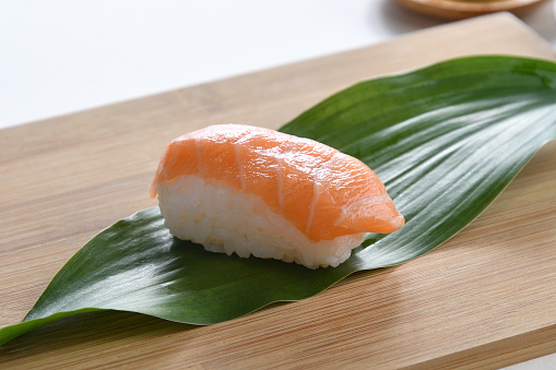 Fresh salmon Nigiri sushi made by placing thinly sliced fresh salmon on a small chunk of vinegared rice and shaping it by hand.