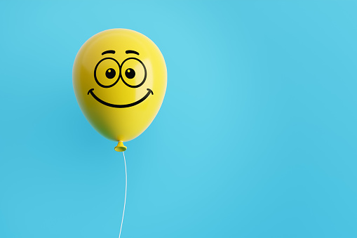 Yellow flying air helium balloon with smiling emoticon face against blue background. Happiness, positivity, optimism concept. 3D rendering.