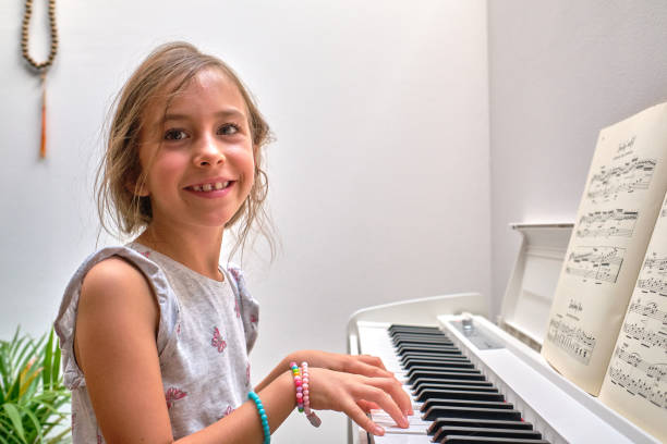 istock Portrait of small smiling girl practicing playing a piano 1422975589