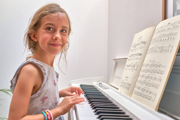 istock Portrait of small smiling girl practicing playing a piano 1422975677