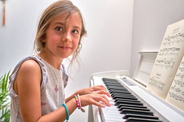 istock Portrait of small smiling girl practicing playing a piano 1422975694