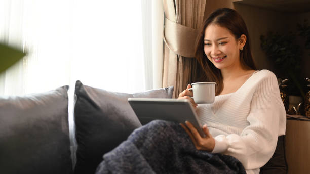 istock Happy woman resting on comfortable couch and using digital tablet, enjoy stress free peaceful mood at the morning. 1422976060