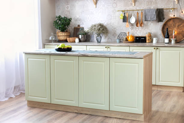 istock Modern home decor. Kitchen utensils, dishes and plates. Kitchen island in dining room. Green wooden kitchen interior with wooden shelf and cozy decoration. Stylish cuisine with flowers in vase. 1422977298