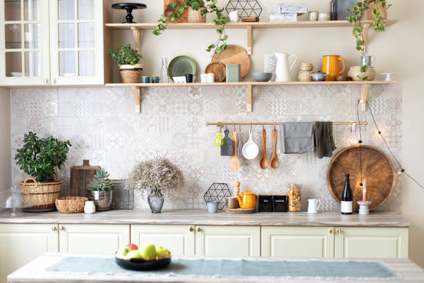 istock Modern home decor. Kitchen utensils, dishes and plates. Kitchen island in dining room. Green wooden kitchen interior with wooden shelf and cozy decoration. Stylish cuisine with flowers in vase. 1422977337