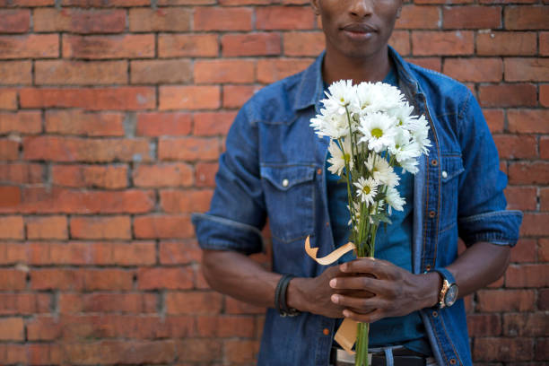 unrecognizable african man holding a bunch of white flowers - men african descent giving flower imagens e fotografias de stock