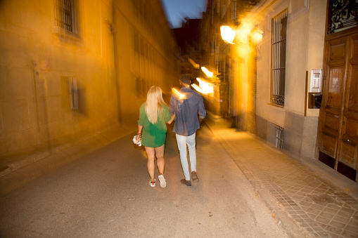 Photo with long exposure of a couple walking in the street at night