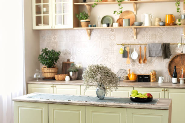 istock Modern home decor. Kitchen utensils, dishes and plates. Kitchen island in dining room. Green wooden kitchen interior with wooden shelf and cozy decoration. Stylish cuisine with flowers in vase. 1422978486