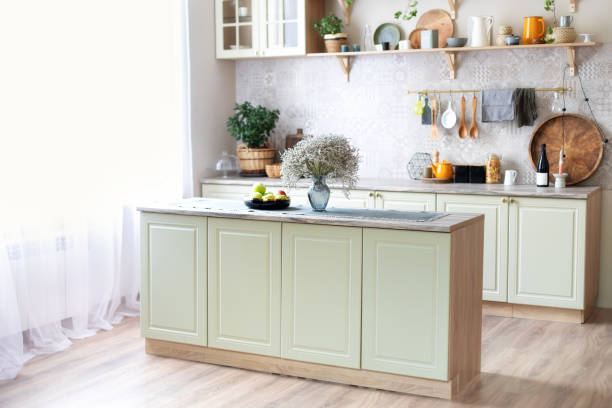 istock Modern home decor. Kitchen utensils, dishes and plates. Kitchen island in dining room. Green wooden kitchen interior with wooden shelf and cozy decoration. Stylish cuisine with flowers in vase. 1422978487