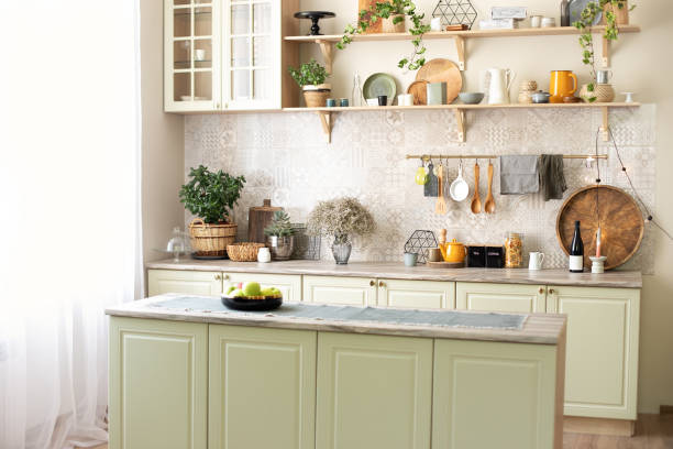 istock Modern home decor. Kitchen utensils, dishes and plates. Kitchen island in dining room. Green wooden kitchen interior with wooden shelf and cozy decoration. Stylish cuisine with flowers in vase. 1422979107