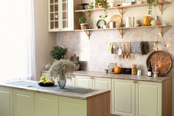 istock Modern home decor. Kitchen utensils, dishes and plates. Kitchen island in dining room. Green wooden kitchen interior with wooden shelf and cozy decoration. Stylish cuisine with flowers in vase. 1422979251