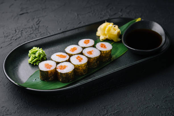 istock Row of fresh maki sushi rolls on black plate 1422988984