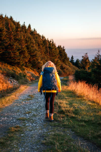 istock Woman with backpack hiking on mountain trail during sunset at autumn 1422989429