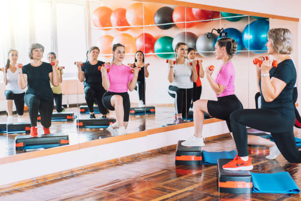 Group of women are engaged in step aerobics with dumbbells in their hands in front of mirror stock photo