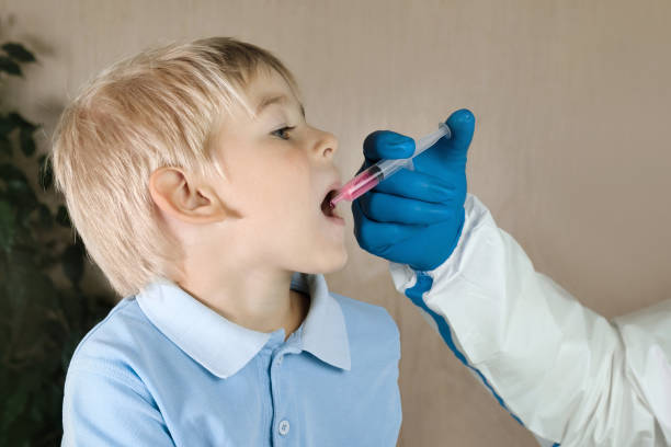 niño que recibe gotas de polio. médico haciendo a la vacunación oral infantil contra la infección. pequeño chico de cabello rubio en el hospital. atención médica infantil y prevención de enfermedades. vía de la vacuna contra la poliomielitis. inmu - vacunación antipoliomielítica fotografías e imágenes de stock