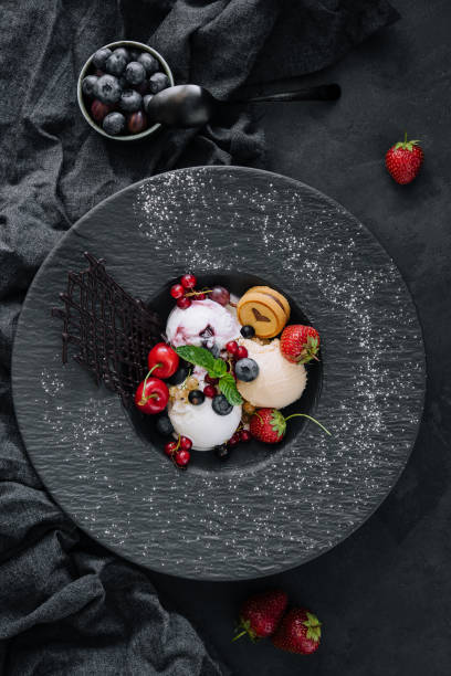istock Vanilla ice cream scoops with fresh berries on black plate 1422991098