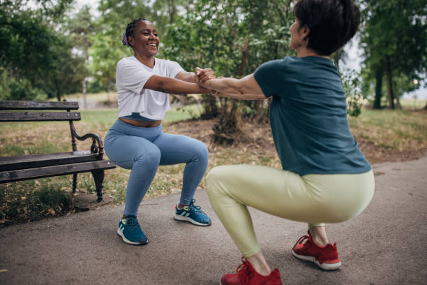 Two women exercising together on a summer day in public park.