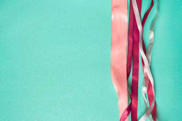 Pink and silver wrapping satin ribbons on cyan color background