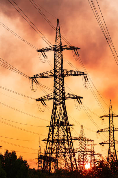 istock Metal construction silhouette. Electrical supply tower shadows on orange sunset. 1422999137