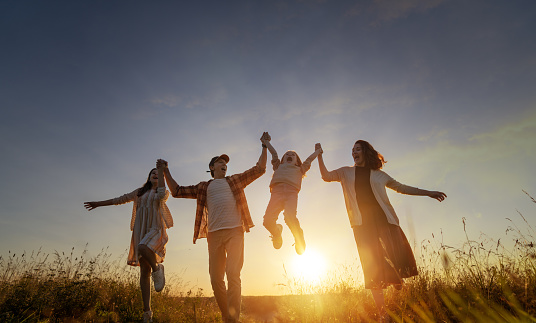 Happy family in the park. Father, mother and children are running, having fun and enjoying summer evening.