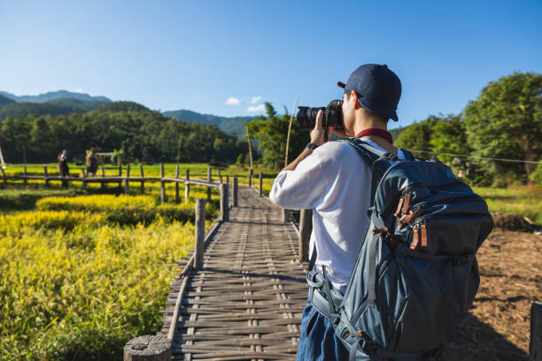 Traveler man with camera travel in Thailand Solo travel relax vacation concept, Young happy asian traveler and photographer man with camera and backpack sightseeing on bamboo bridge with rice field at Boon Kho Koo So, Chiang Mai, Thailand bamboo bridge stock pictures, royalty-free photos & images