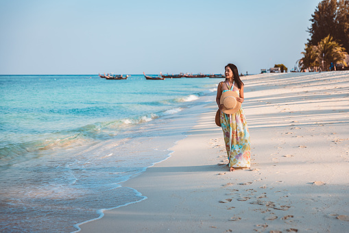 Summer travel vacation concept, Happy traveler asian woman with dress relax and sightseeing on beach in evening at Koh Lipe, Satun, Thailand