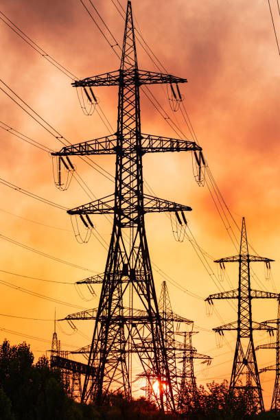 istock Shadows ofEnergy transmission towers. High voltage tower silhouette sunset. 1423002609